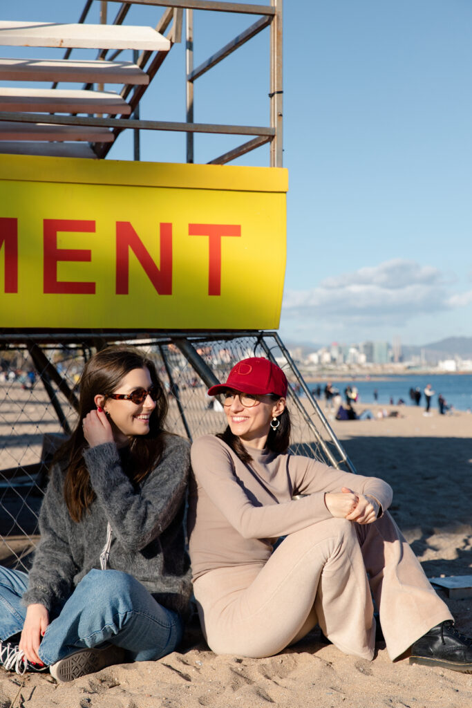 Koleżanki siedzące przy budce ratownika na plaży w Barcelonie.