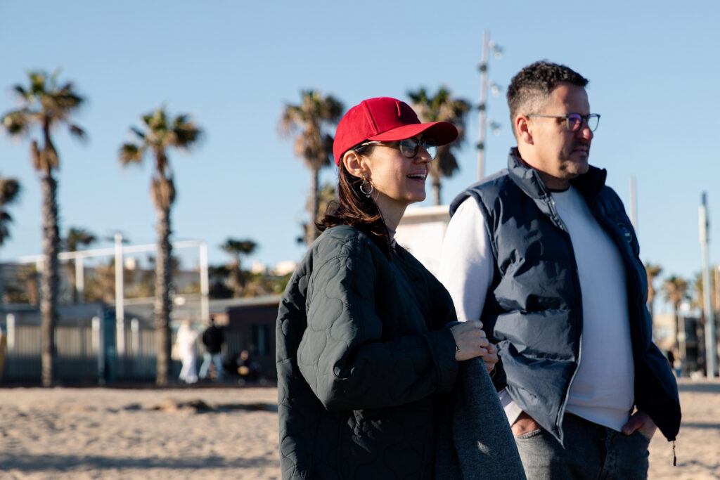 Sylwetki rodziny na tle morza podczas zachodu słońca na plaży w Barcelonie.