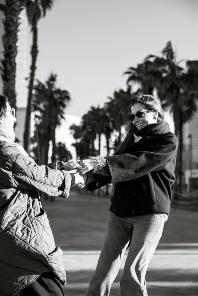 Uśmiechnięta mama z córką na tle palm w Barcelonie.